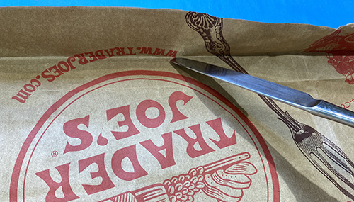 folding the sides of the brown paper grocery bag to tear rough edges