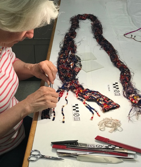 Catherine working to separate the warp threads into groups sharing the same dyed pattern.