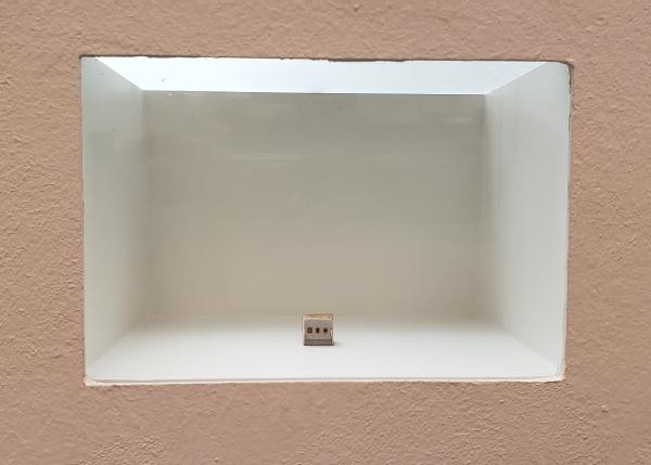 A tiny gallery of oil paintings displayed in a wall vitrine