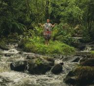 Figure in colorful costume standing next to a woodland stream