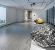 Installation photograph, featuring Zhan Wang's Beyond 12 Nautical Miles Floating Rock Drifts on the Open Sea (2000) and Gold Mountain (2007), in the exhibition The Allure of Matter: Material Art from China