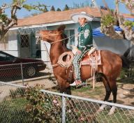 Man riding horse in front of a house